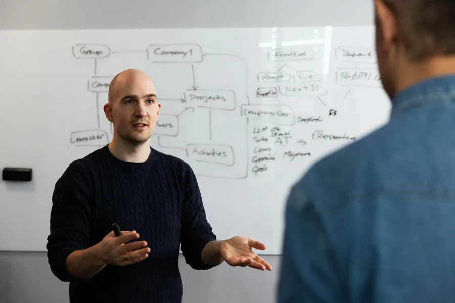 Two colleagues working through a diagram on a whiteboard