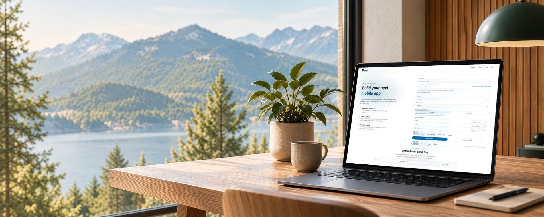 A laptop on a wooden desk by a window, showing Softeria Studio being asked to build an app, with a plant and a mug beside it and forest, water and mountains outside